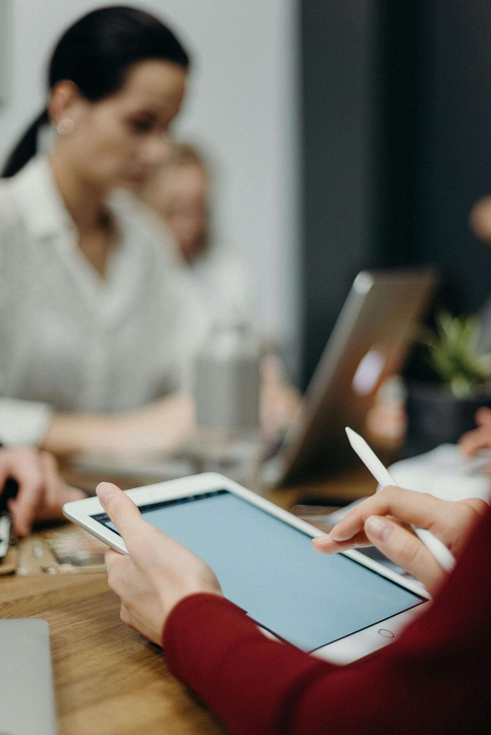 A focused team meeting showcasing digital collaboration with tablets and laptops in an office setting.